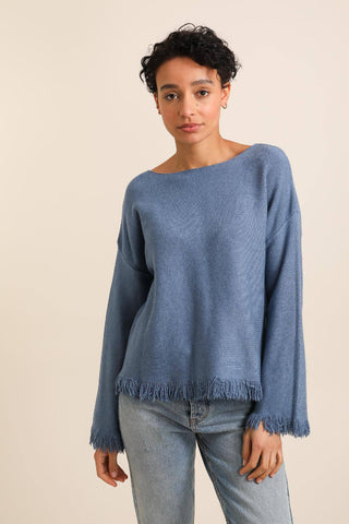 Sinisessä April-neulepuserossa hapsut hihansuissa ja helmassa. Susanne